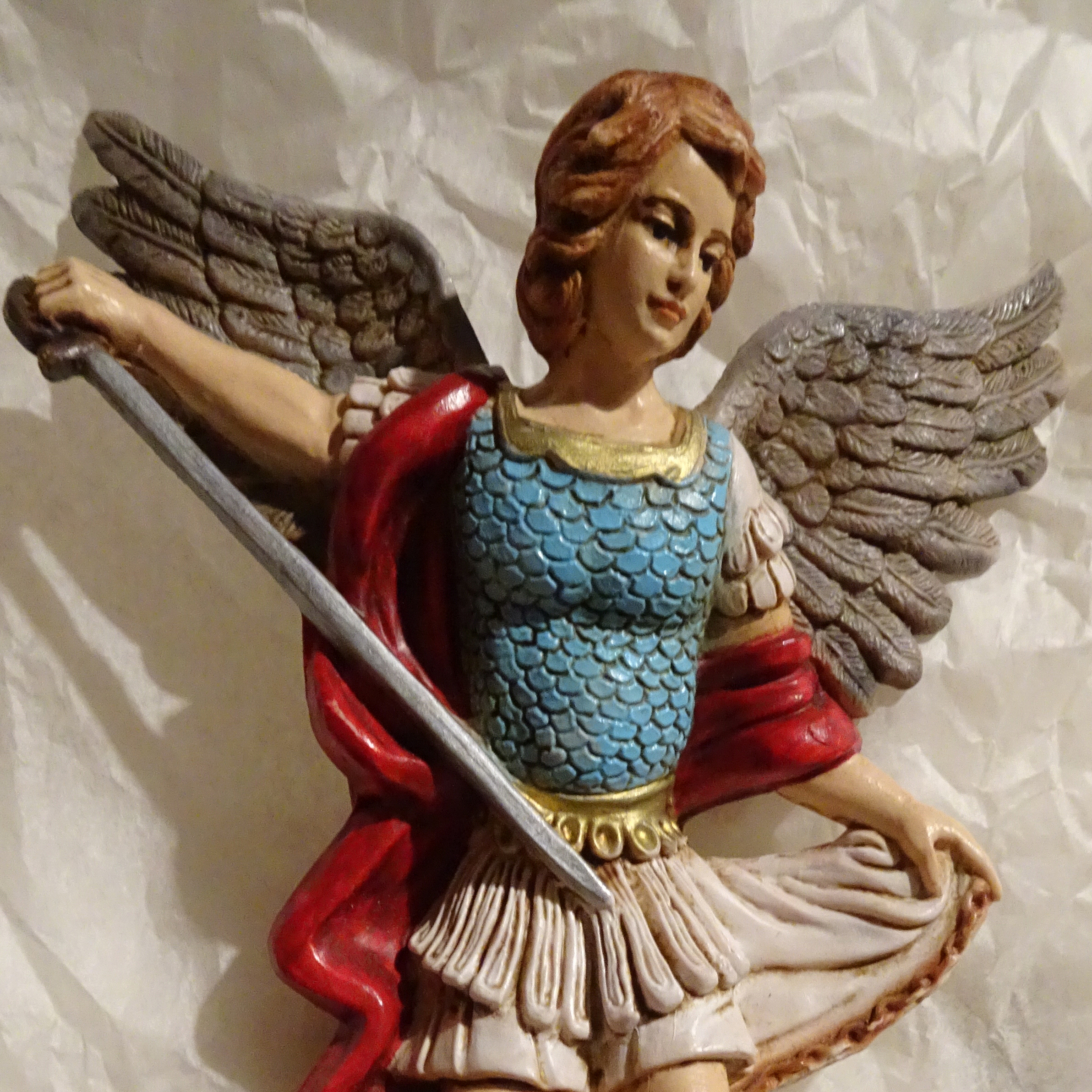 Polychrome resin figure of a female St Michael standing over Satan, with drawn sword, holding her skirt/mantle out with her left hand 